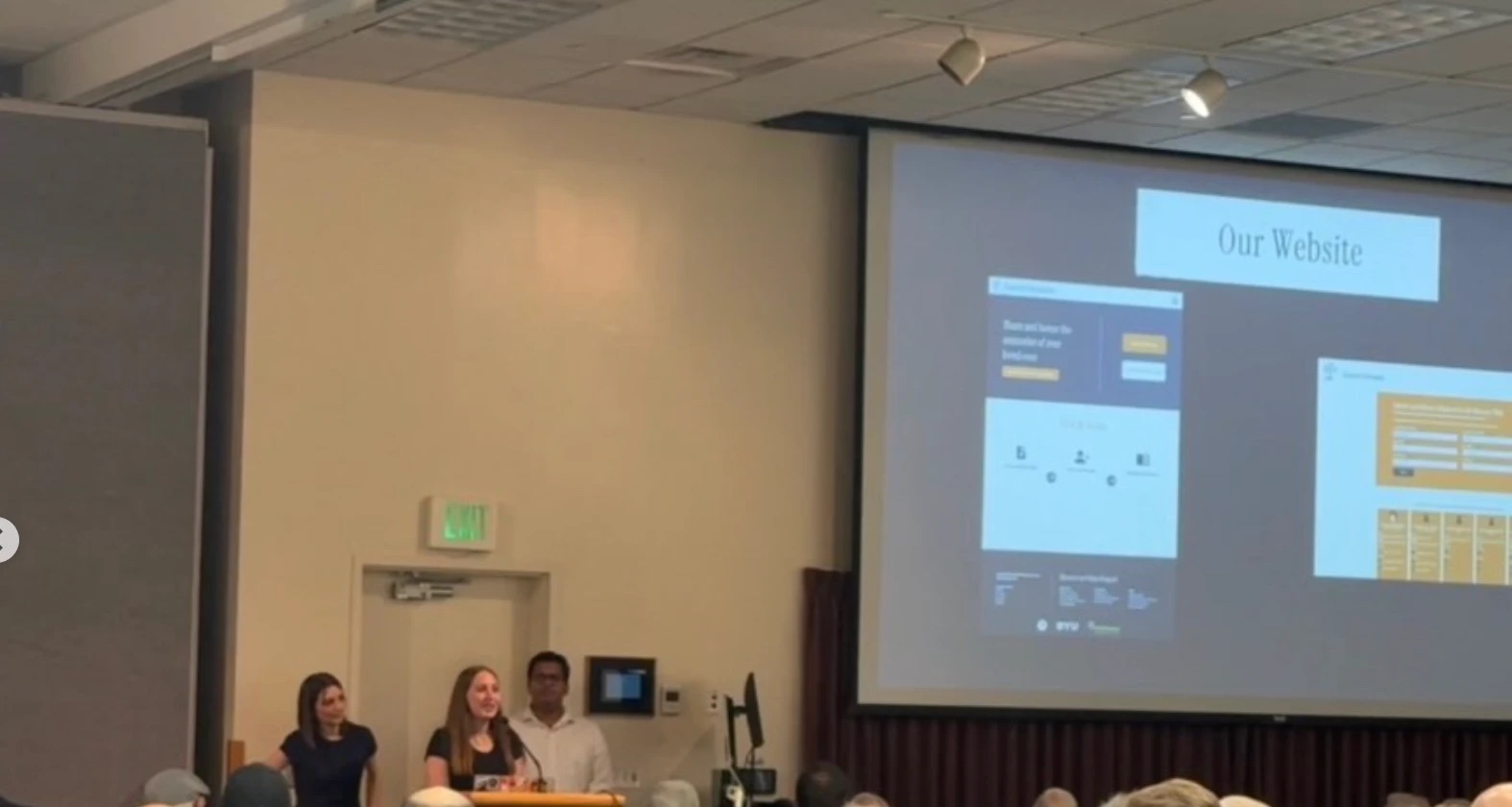 Three presenters at a podium in a conference room, with a projected slide titled Our Website showing Funeral Memories screens